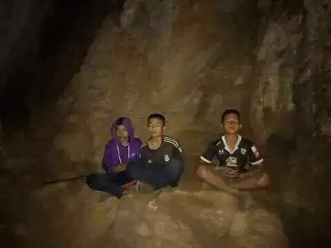Three boys meditating inside a cave