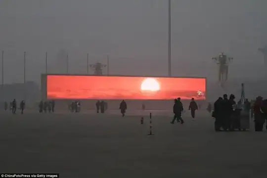 Heavily smogged/fogged Chinese square with giant widescreen display showing a red sunrise.