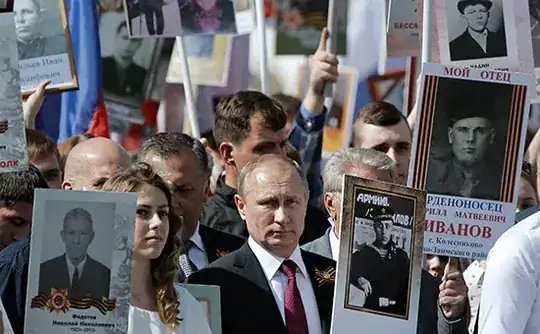 Russian president Putin marching with a portrait of his father