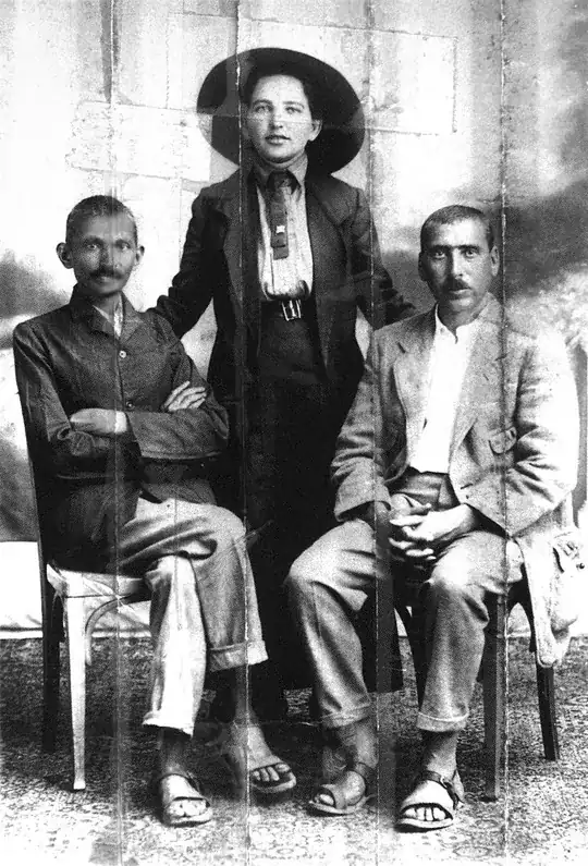 Gandhi (left), Sonia Schlesin, his secretary, and Dr. Hermann Kallenbach. Kallenbach sewed this photo in the collar of his jacket before joining Gandhi in England during the First World War. Being of German origin, he feared being arrested and the image seized. He was effectively arrested, but the police never discovered the photo. This photo has been retouched to diminish the creasing of the picture